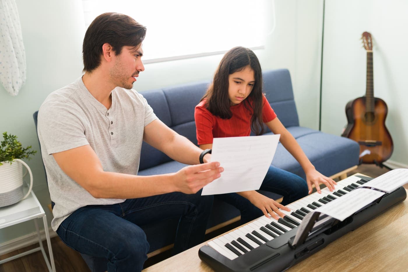 Profesor de piano enseñando a un alumno a leer una partitura
